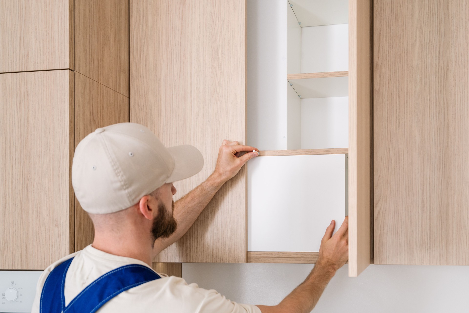 Handyman installs new wooden cabinet doors in modern kitchen renovation