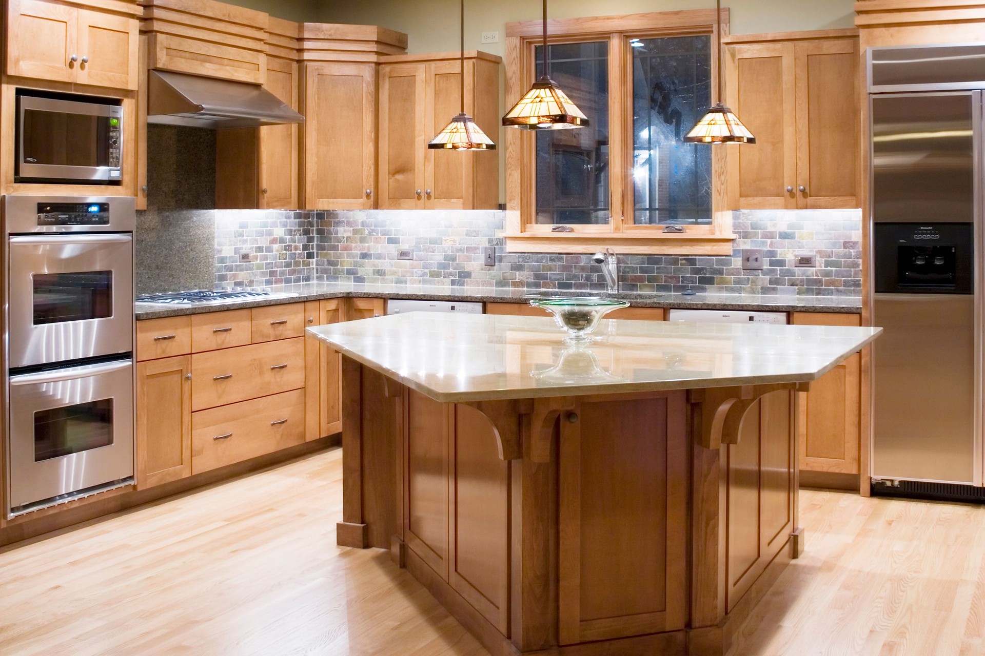 A wood kitchen with island and steel appliances